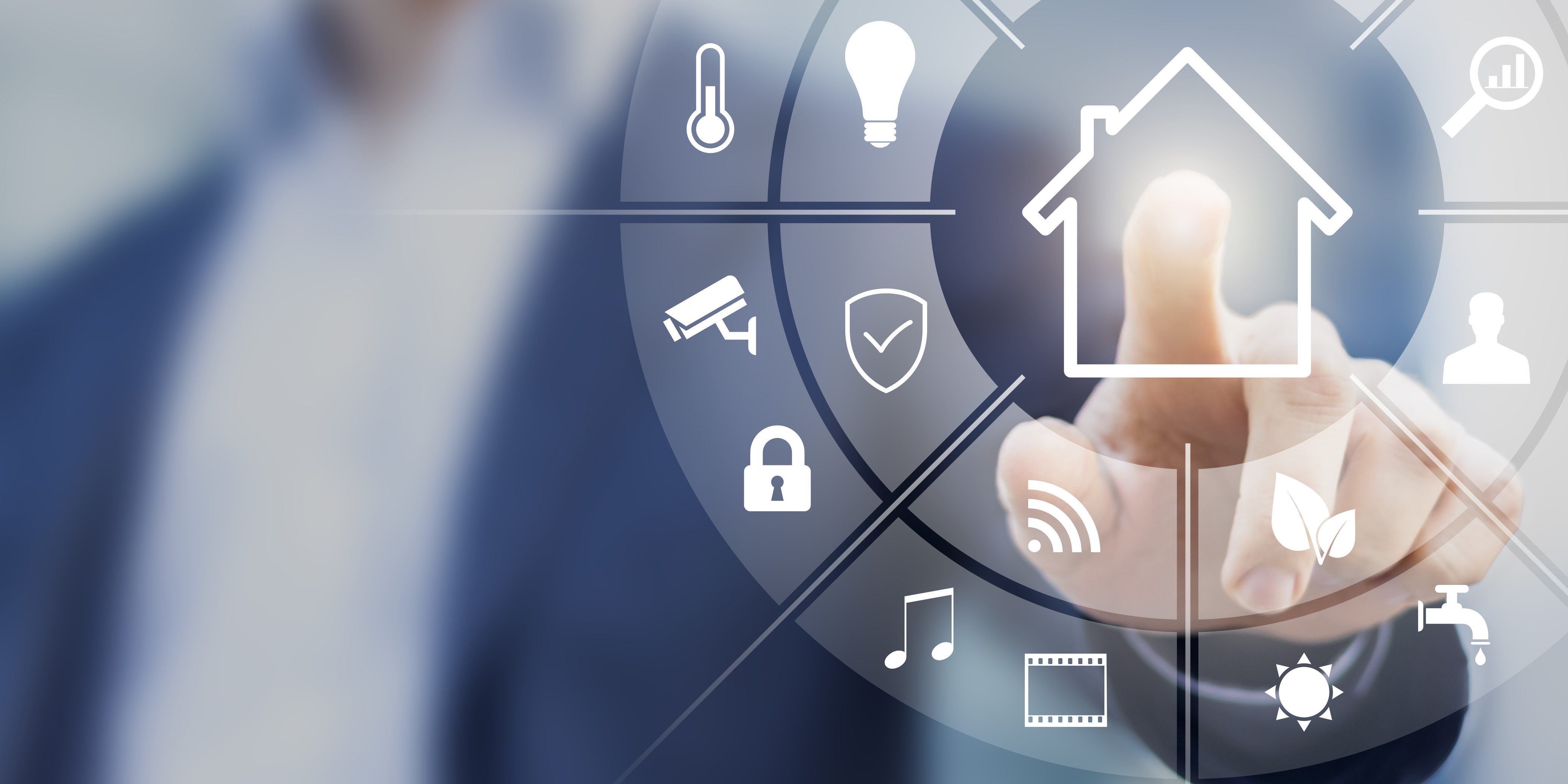 Ein Finger deutet auf ein schwebendes, halbtransparentes Touchscreen-Interface mit verschiedenen Symbolen. Diese Symbole stellen Funktionen der Hausautomation dar, wie Überwachung, Temperatur, Musik und Licht. Im Hintergrund ist eine Person unscharf zu sehen.