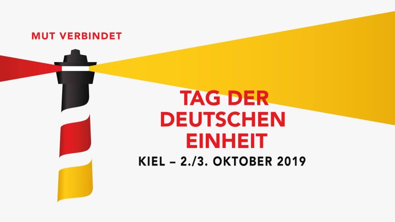 Grafik einer schwarz-rot-goldenen Leuchtturm-Illustration. Daneben der Text: „Tag der Deutschen Einheit“. Oben „Mut verbindet“. Unten: „Kiel – 2./3. Oktober 2019“. Hintergrund ist weiß.