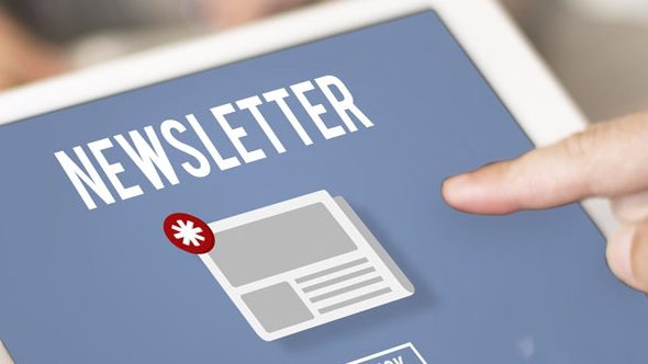 Ein Finger zeigt auf ein Tablet-Bildschirm mit der Aufschrift "Newsletter". Auf dem Bildschirm ist ein Symbol eines Briefes mit einem Sternchen darauf zu sehen. Der Hintergrund ist unscharf.
